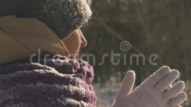 一位在户外散步的年轻女子在冬天的公园里散步时，她用手臂呼吸以保暖